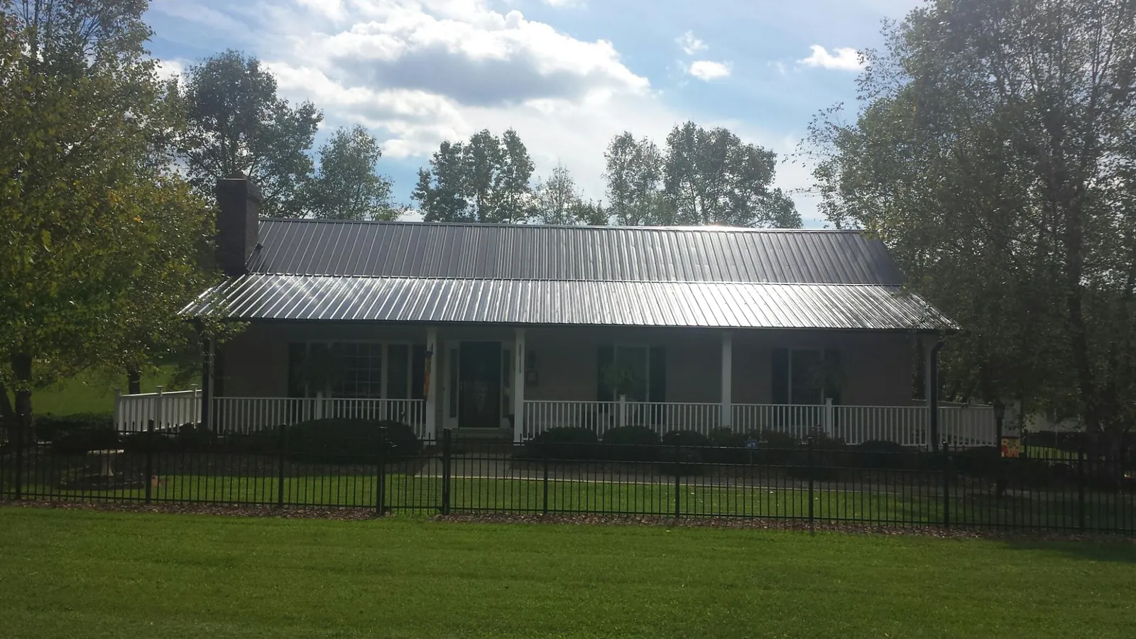 Gray metal roof on a brick ranch with a full width front porch — Gutter Guard Installation work by our crew in Frederick